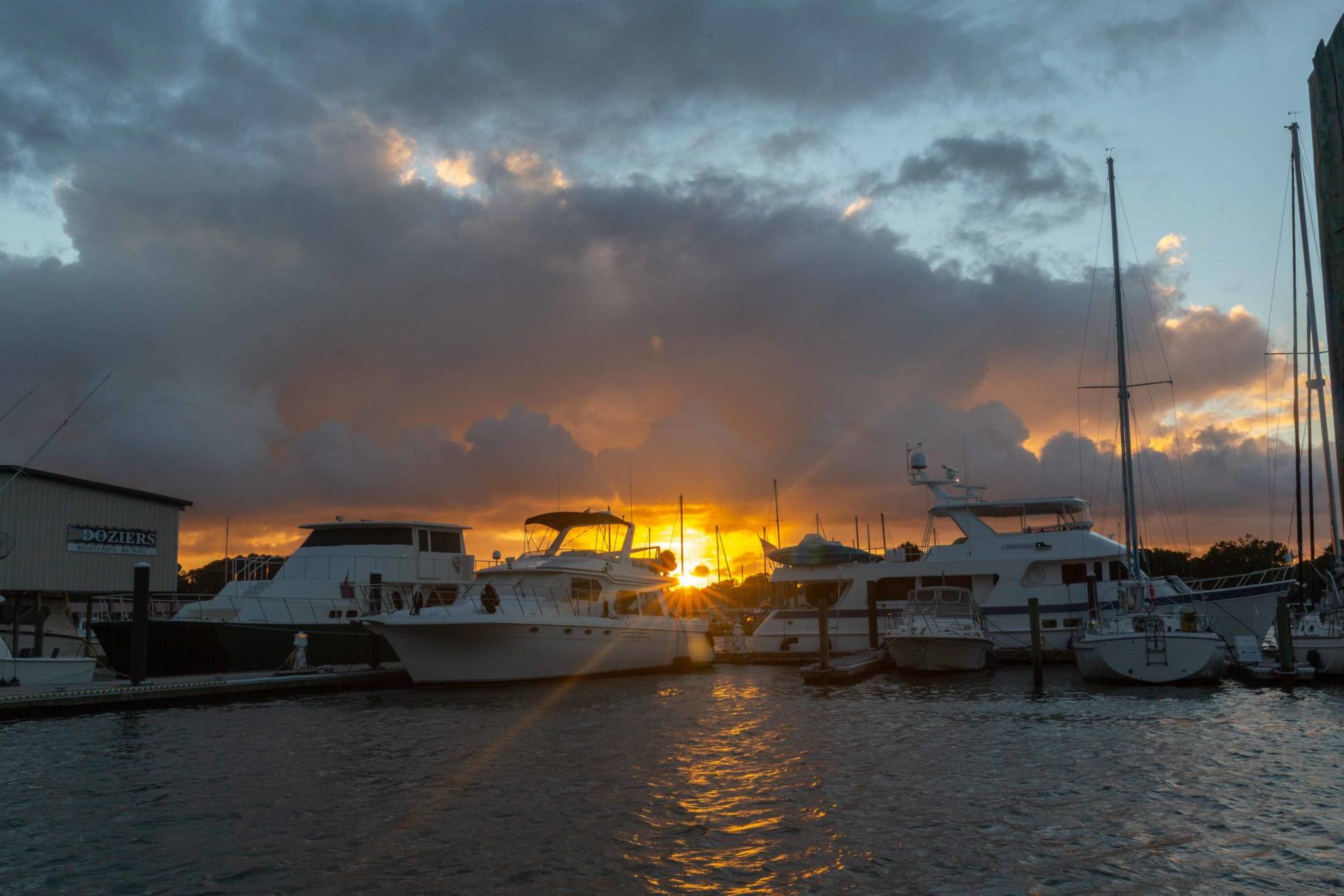 clouds and sunburst at sunset with boats